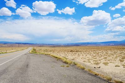 Road leading towards landscape against sky