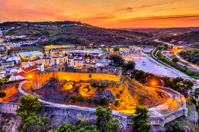 High angle view of illuminated buildings in city at sunset