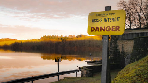 Information sign by lake against sky