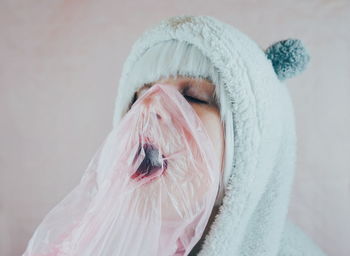 Close-up of woman in costume with pink plastic against wall