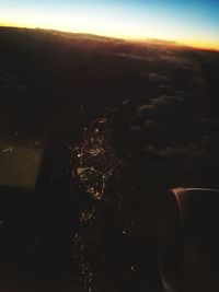 Close-up of airplane over sea against sky during sunset