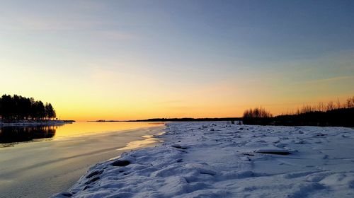 Scenic view of frozen lake against sky during sunset