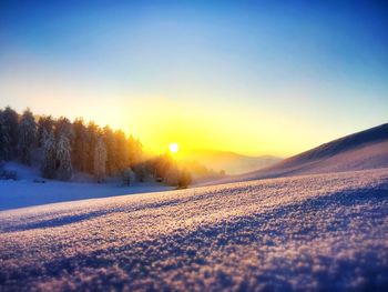 Scenic view of snow covered landscape against sky during sunset