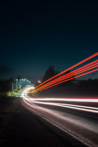 Light trails on road against sky at night