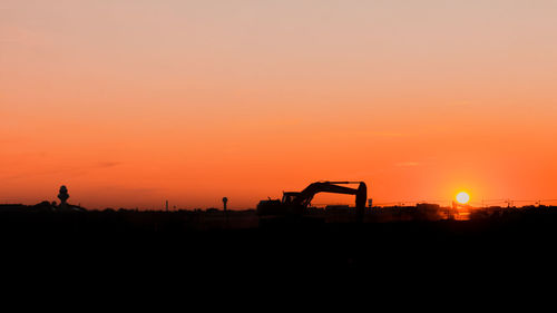 Silhouette construction site against clear sky during sunset