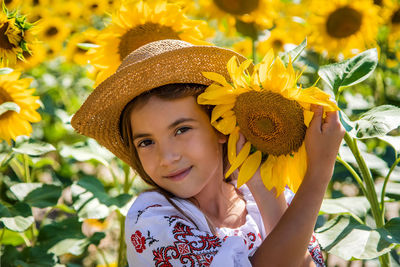 Portrait of smiling girl with sunflower at field