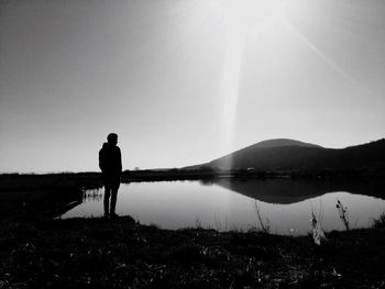 Rear view of man overlooking calm lake