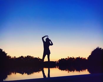 Silhouette of people standing against clear sky at sunset