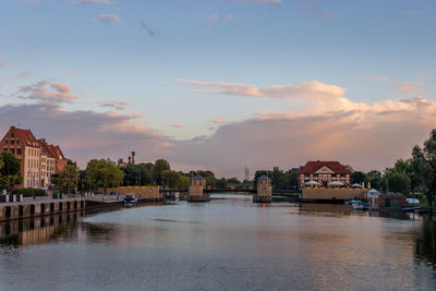 River by buildings against sky during sunset