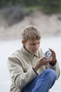 Close-up of teenage boy photographing with small digital camera