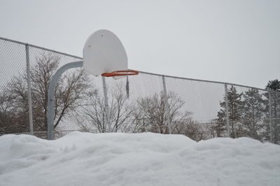 View of basketball hoop on snowy field against clear sky