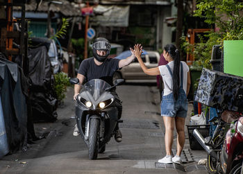 Motorcyclist giving a "high five" to woman in back alley