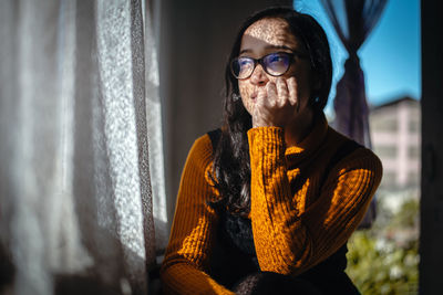 Portrait of man wearing eyeglasses at window