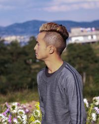 Young man looking away while standing on land