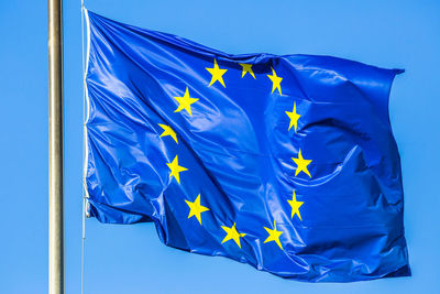 Low angle view of flags against blue sky