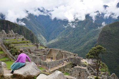 Rear view of woman sitting on rock at machu picchu