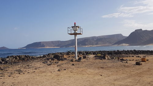 Sign board on beach against sky