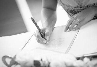 Midsection of woman writing on paper at table