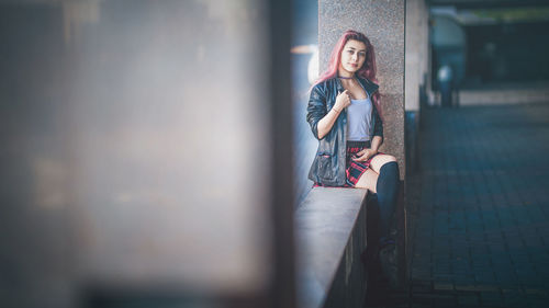 Portrait of woman sitting on retaining wall