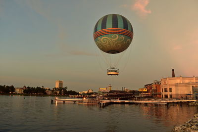 Hot air balloon flying over water against sky during sunset