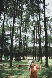 Rear view of woman standing on field in forest