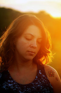 Close-up of woman looking down during sunset