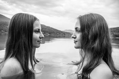 Profile view of shirtless female friends face to face in lake