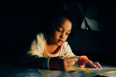 Cute girl looking at stickers in darkroom