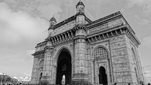 Low angle view of gateway to india against cloudy sky