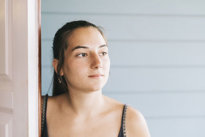 Thoughtful young woman by door
