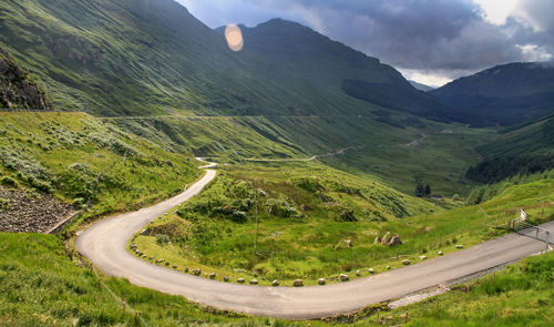 Scenic view of road by mountains against sky