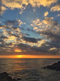 Scenic view of sea against cloudy sky at sunset