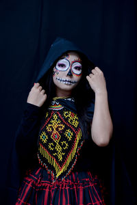 Full length portrait of woman wearing mask against black background