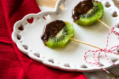 High angle view of chocolate on kiwi slice in heart shape plate