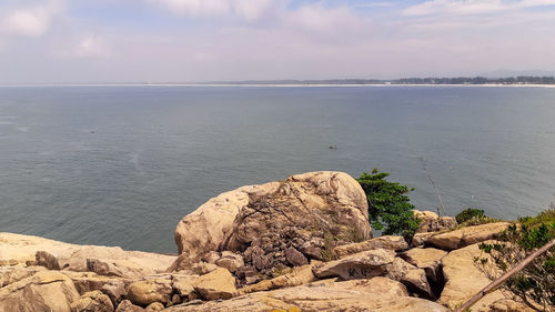 Scenic view of rocks by sea against sky
