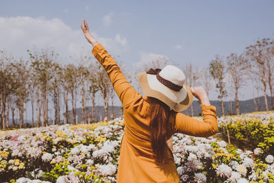 Midsection of woman standing by flowering plants against sky