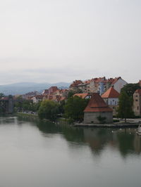 Houses by river against sky in town