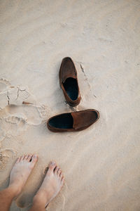 Low section of man standing on sand at beach