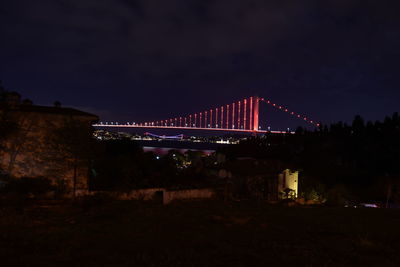 Illuminated bridge over river in city at night