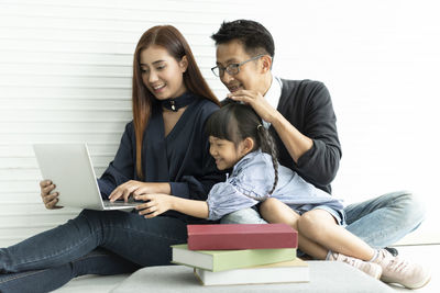 Smiling family looking at laptop while sitting against wall