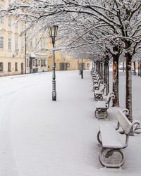 Snow covered street by building in city