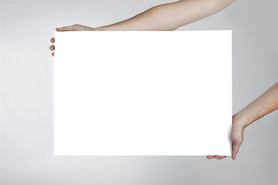 Midsection of person holding paper against white background