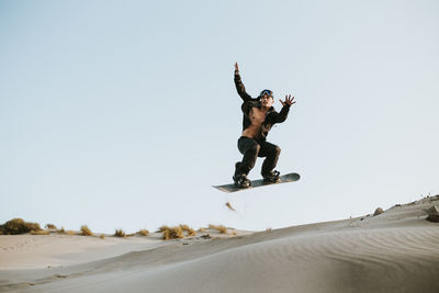 Man sandboarding over sand dunes at almeria, tabernas desert, spain
