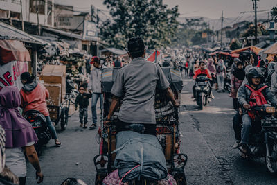 Rear view of people bicycling on road in city