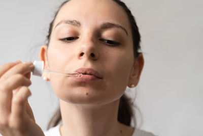 Young woman applying make-up against white background