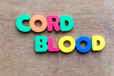 High angle view of colorful cord blood text on wooden table