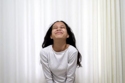 Portrait of teenage girl standing against curtain