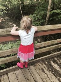 High angle view of girl standing on wooden railing