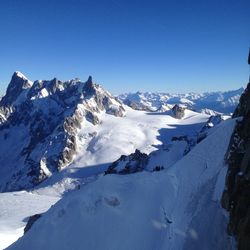 Scenic view of snowcapped mountains against clear blue sky