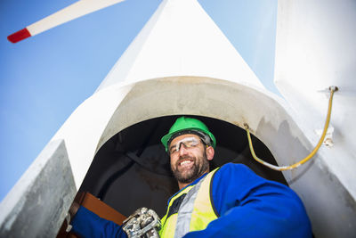 Engineer inspecting wind turbine, using wrench